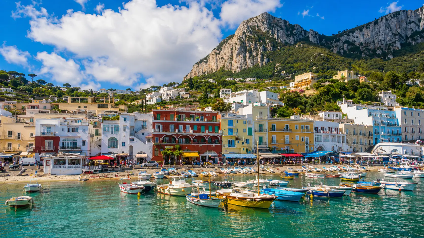 Panorama italiano con colline, mare, cipressi e città storica al tramonto
